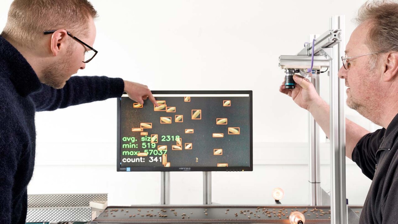 Zwei Wissenschaftler im DIL e.V. arbeiten an einem Kamerasystem zur automatisierten optischen Qualitätskontrolle von Getreidekörnern auf einem Förderband, die Bildanalyse und Statistikdaten werden auf einem Monitor angezeigt